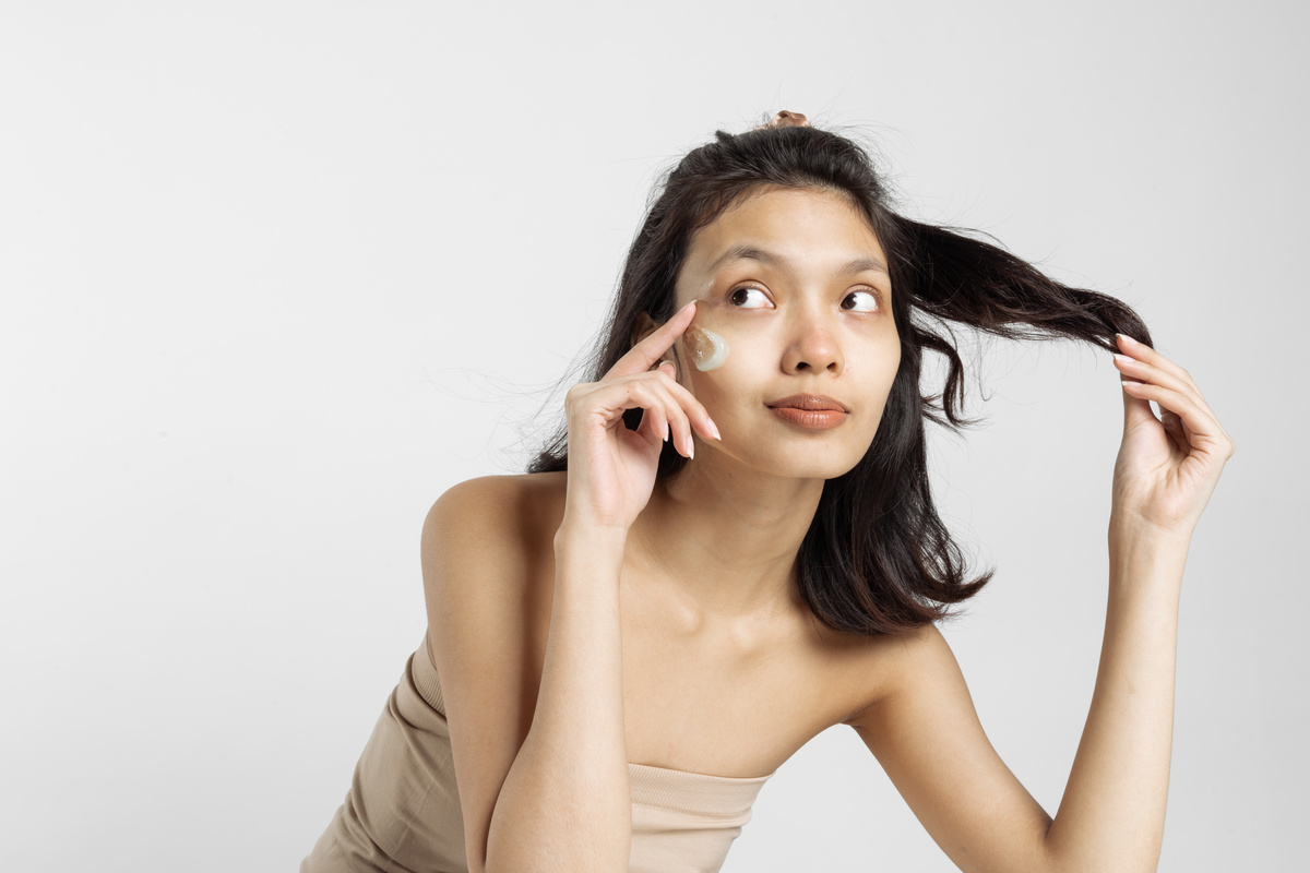 Portrait of Woman with Facial Moisturizer Touching Her Hair